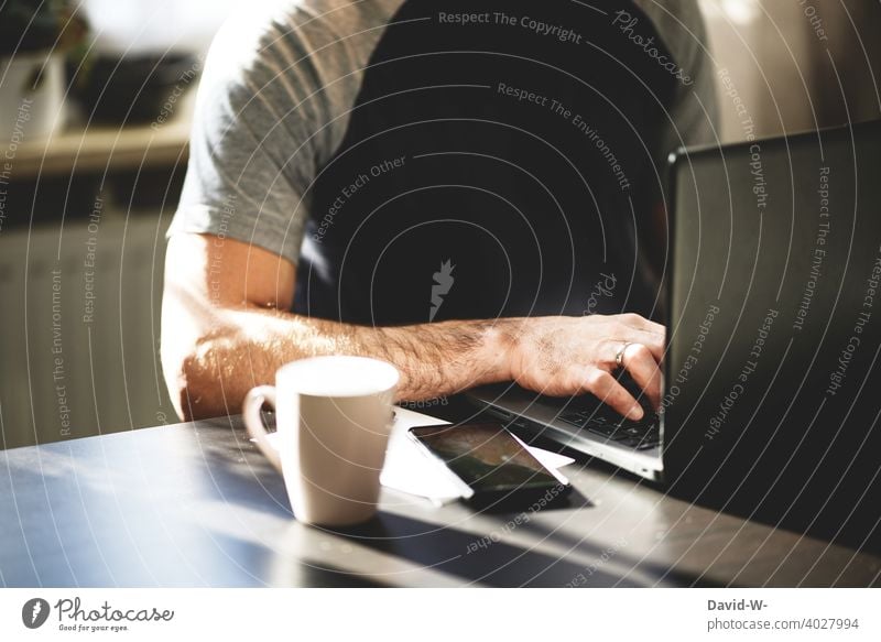 Mann sitzt an einem Tisch am Laptop und tippt mit den Finger auf der Tastatur Notebook tippen Internet digital Tippen modern Technik & Technologie Homeoffice