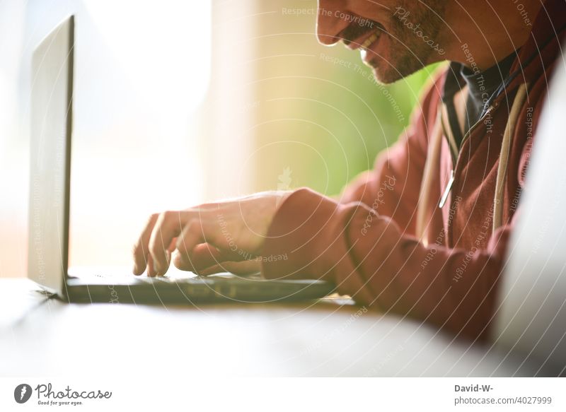 Mann arbeitet zufrieden am Laptop arbeiten Optimismus Fröhlichkeit zu Hause Homeoffice Notebook Tippen lächeln Schreibtisch