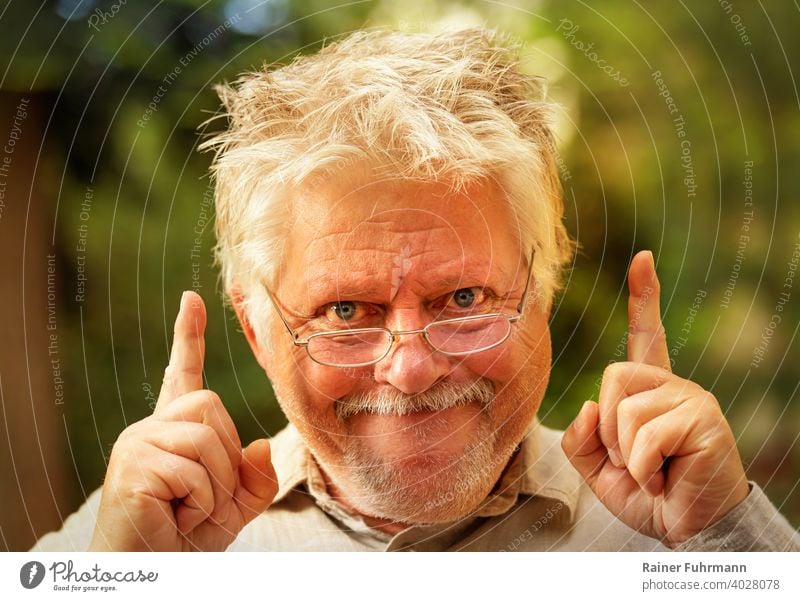 ein seltsamer Mann mit Brille hat plötzlich eine Idee Einfall Erkenntnis Einsicht Entdeckung Porträt wirr grinsen Freude Finger zeigen draußen Garten Park