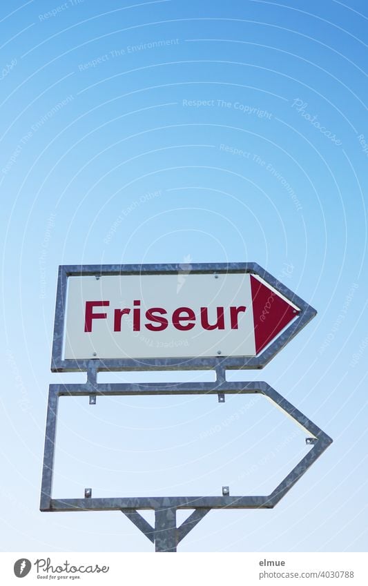 Hinweisschild mit roter Druckschrift "Friseur" sowie ein leerer Rahmen für ein weiteres Schild vor blauem Himmel / Friseurtermin Frisör Hairstylist