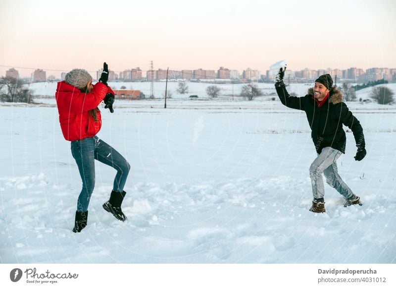 Fröhliches Paar spielt Schneebälle im Winter Feld Schneeball Spaß haben spielen heiter genießen Zusammensein Landschaft Liebe romantisch Partnerschaft Zuneigung