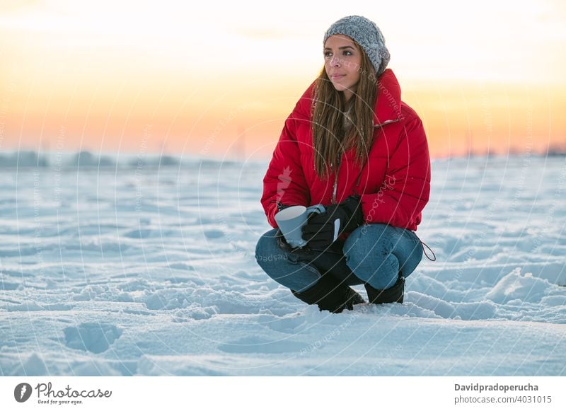 Frau mit Tasse Kaffee ruht in verschneiten Feld Winter Wanderer Schnee trinken ruhen Sonnenuntergang Natur kalt Windstille nachdenken Becher Heißgetränk Abend