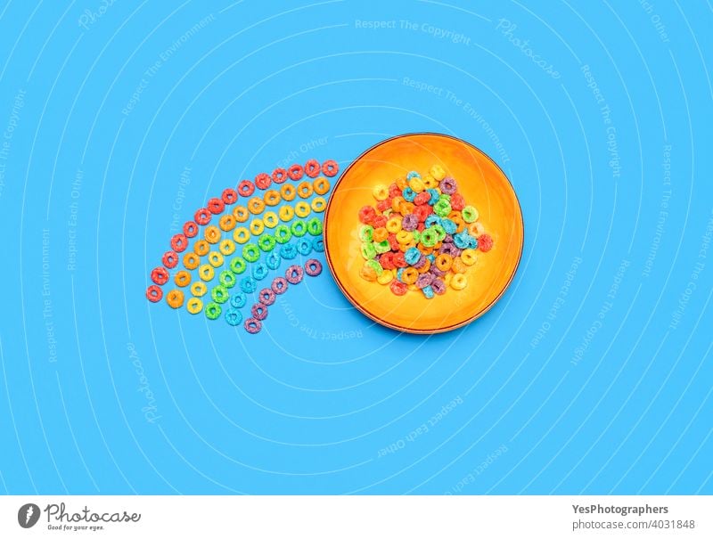 Müslischale isoliert auf blauem Hintergrund. Regenbogen-Fruchtgeschmack Ring Cerealien, Ansicht von oben obere Ansicht sortiert Blauer Hintergrund