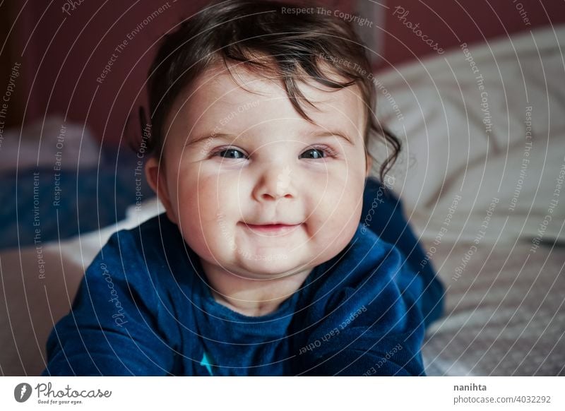 Kleines Baby in Blau liegt auf einem Bett Säuglingsalter niedlich lieblich Mädchen Schlafzimmer heimwärts Familie bezaubernd blau Pyjama spielerisch Gesicht