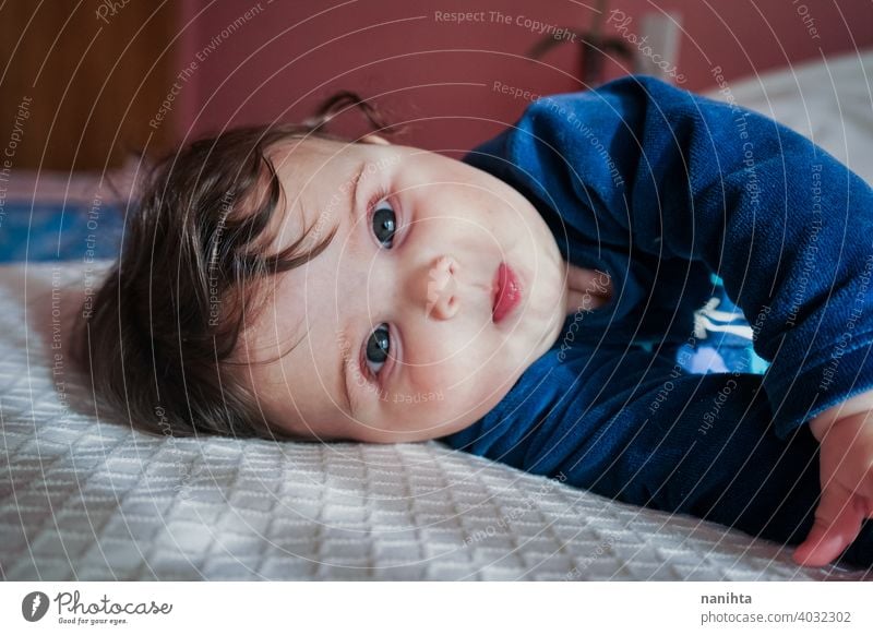 Kleines Baby in Blau liegt auf einem Bett Säuglingsalter niedlich lieblich Mädchen Schlafzimmer heimwärts Familie bezaubernd blau Pyjama spielerisch Gesicht