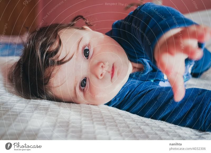 Kleines Baby in Blau liegt auf einem Bett Säuglingsalter niedlich lieblich Mädchen Schlafzimmer heimwärts Familie bezaubernd blau Pyjama spielerisch Gesicht