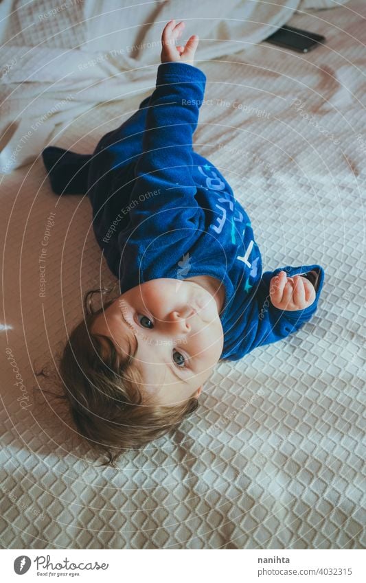 Kleines Baby in Blau liegt auf einem Bett Säuglingsalter niedlich lieblich Mädchen Schlafzimmer heimwärts Familie bezaubernd blau Pyjama spielerisch Gesicht