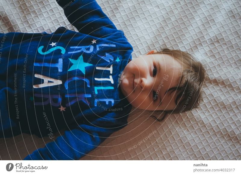 Kleines Baby in Blau liegt auf einem Bett Säuglingsalter niedlich lieblich Mädchen Schlafzimmer heimwärts Familie bezaubernd blau Pyjama spielerisch Gesicht