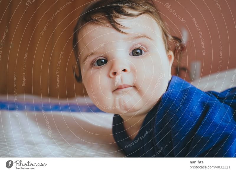 Kleines Baby in Blau liegt auf einem Bett Säuglingsalter niedlich lieblich Mädchen Schlafzimmer heimwärts Familie bezaubernd blau Pyjama spielerisch Gesicht