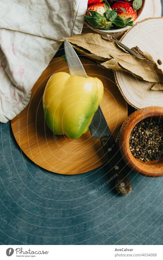 Attrappe eines Kochtisches mit einer halbierten Paprika, einem Messer und einigen Gewürzen Leinwand Essen zubereiten Karotten Altholz horizontal produzieren