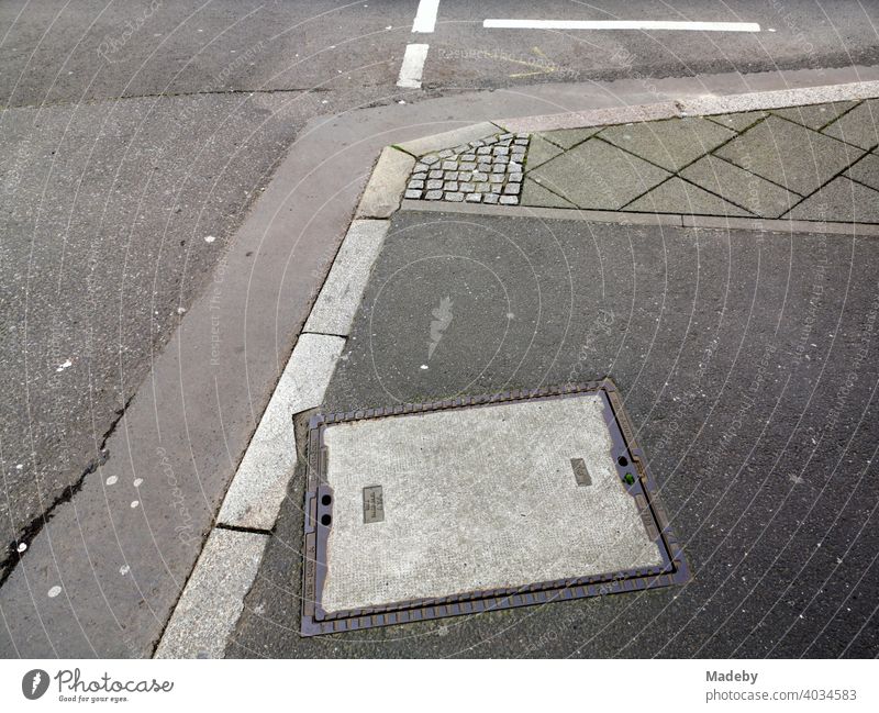 Straßenecke mit Bordstein, Asphalt und verschiedenen grauen Pflastersteinen in Frankfurt am Main in Hessen Kreuzung Gully Gullydeckel Kanalisation Grau Grautöne