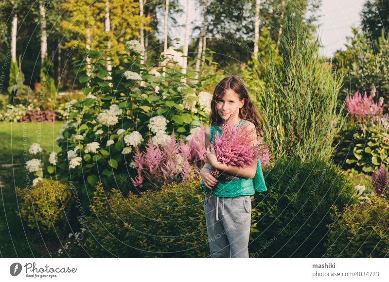 glückliches Kind Mädchen Kommissionierung Bouquet von Astilbe Blumen im Sommer Garten Natur Kindheit im Freien Glück Fröhlichkeit grün niedlich Spaß wenig