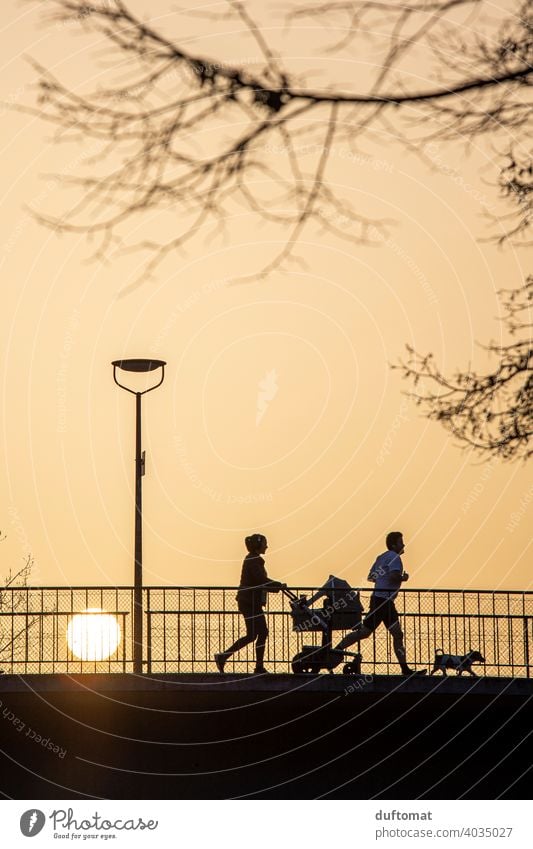 Gegenlichtaufnahme von Familie bei Sonnenuntergang Silhouette joggen laufen Saharasand Joggen Sport Fitness Bewegung Kinderwagen Sonnenlicht Gesundheit