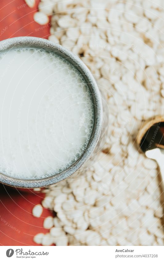 Ein Metalllöffel über ein Bündel Haferkörner mit einer Tasse Hafermilch Gesundheit melken Lebensmittel trinken organisch Diät Ernährung Vegetarier natürlich