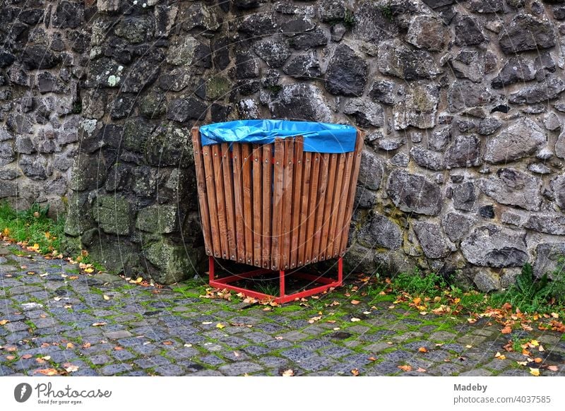 Mülleimer aus braunem Holz ausgelegt mit blauem Plastiksack vor altem Mauerwerk im Burghof von Burg Gleiberg in Wettenberg Krofdorf-Gleiberg bei Gießen in Hessen