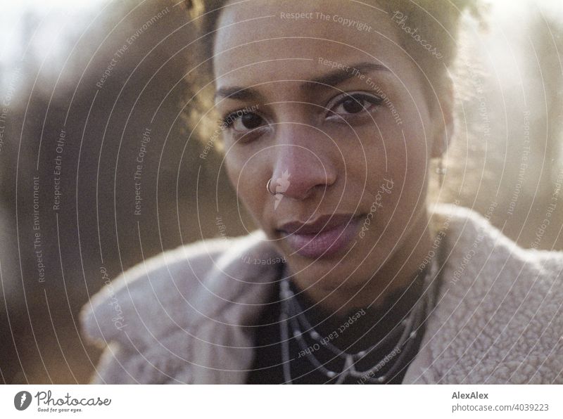 Junge Frau steht in der Natur an einem See - analoges Gegenlicht- Portrait sportlich dunkelhaarig langhaarig hübsch stark zierlich natürlich lockig schlank Aus