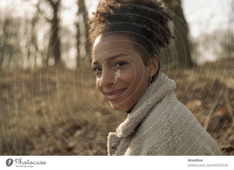 Junge Frau steht in der Natur an einem See und lächelt - analoges  Portrait sportlich dunkelhaarig langhaarig hübsch stark zierlich natürlich lockig schlank Aus