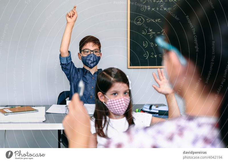 Schüler mit Masken heben die Hände in der Schule Handreichung Coronavirus Gesichtsmaske neue Normale teilnehmend Lehrerin Sicherheit Virus Menschen Mädchen