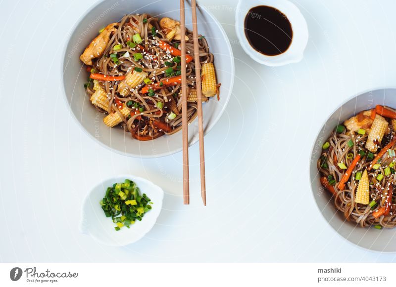 Japanische rühren gebraten Buchweizen Soba-Nudeln mit Huhn und Gemüse - Karotte, Zwiebel und Baby-Mais in Schüssel auf weißem Hintergrund serviert soba