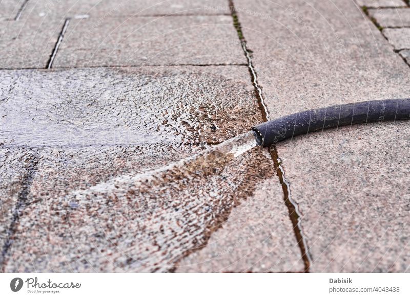 Auslaufendes Wasser aus einem Schlauch auf einer Stadtstraße Straße Röhren Tube Schaden im Freien fließen Pipeline Gerät Druck Konstruktion Gefahr Großstadt