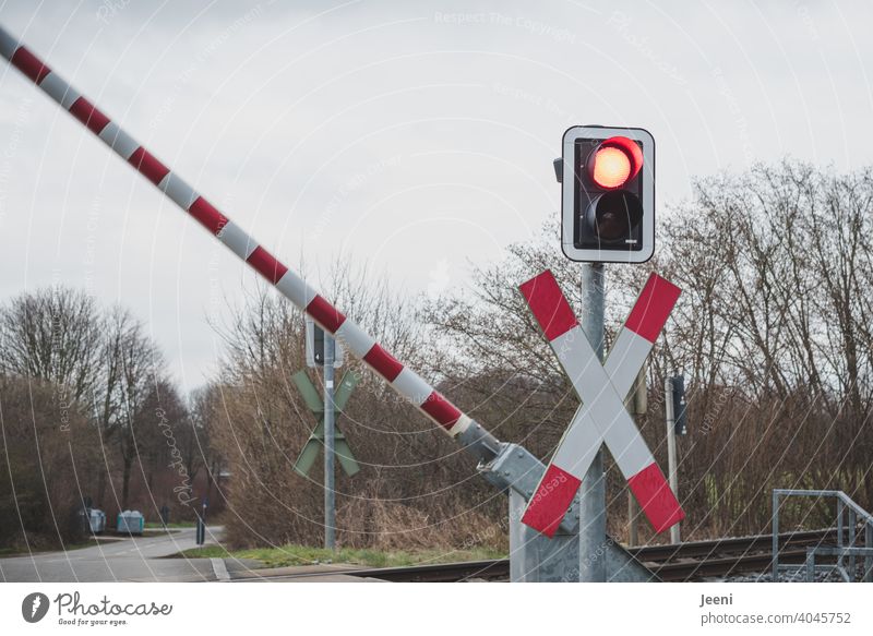 Achtung! Jetzt erstmal den Zug abwarten - die Bahnschranke schließt sich in diesem Moment Bahnübergang Andreaskreuz gelb Schranke Bahnschienen