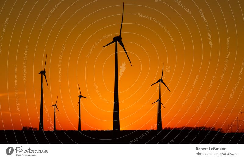 viele Windräder bei Sonnenuntergang stehen auf einem Feld und produzieren Strom windräder ökostrom umweltfreundlich klimaschutz abendrot sonnenuntergang