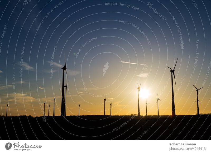 viele Windräder bei Sonnenuntergang stehen auf einem Feld und produzieren Strom windräder ökostrom umweltfreundlich klimaschutz abendrot sonnenuntergang