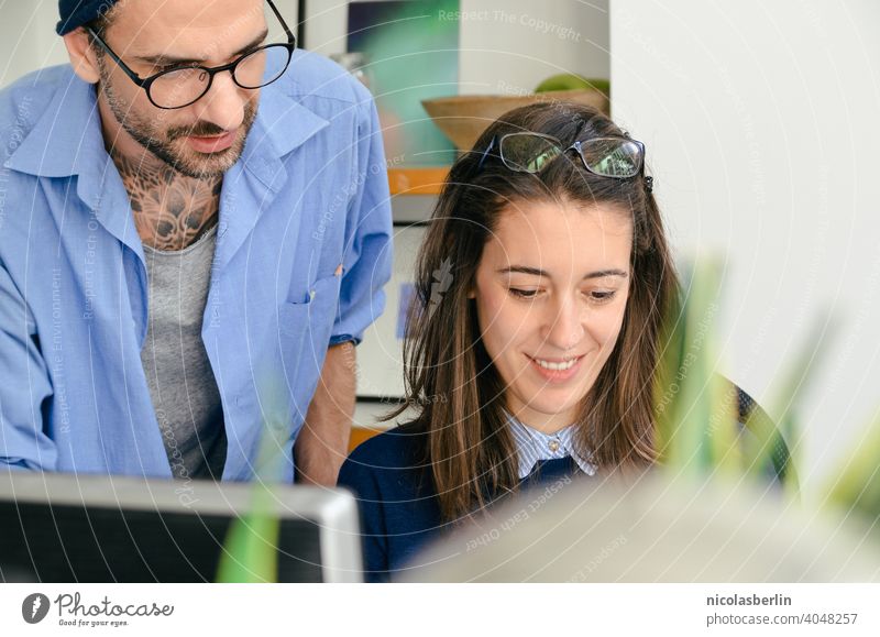 Junger Mann und fröhliche Frau arbeitet am Computer im Büro Freiberufliche Tätigkeit Verwendung des Laptops Hipster Technik & Technologie Drahtlos Jahrtausende