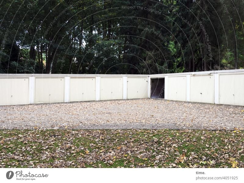 schwarzes Loch Garage Garagentor verschlossen offen Kies Platz wiese laub herbstlaub wald bäume menschenleer