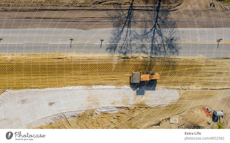 Luftaufnahme auf Straßenwalze mit Spikes arbeitet auf der Baustelle, Verdichtung der Basis für Asphaltstraße oben Antenne Tiefbau kompakt Verdichten Verdichter