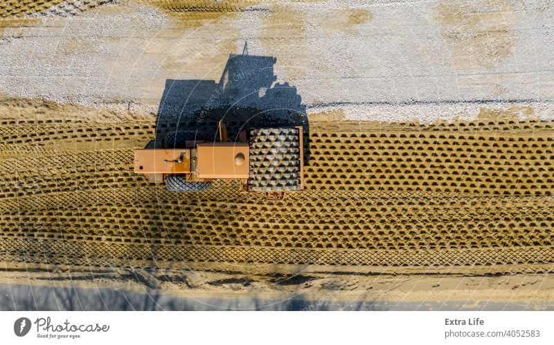 Luftaufnahme auf Straßenwalze mit Spikes arbeitet auf der Baustelle, Verdichtung der Basis für Asphaltstraße oben Antenne Tiefbau kompakt Verdichten Verdichter