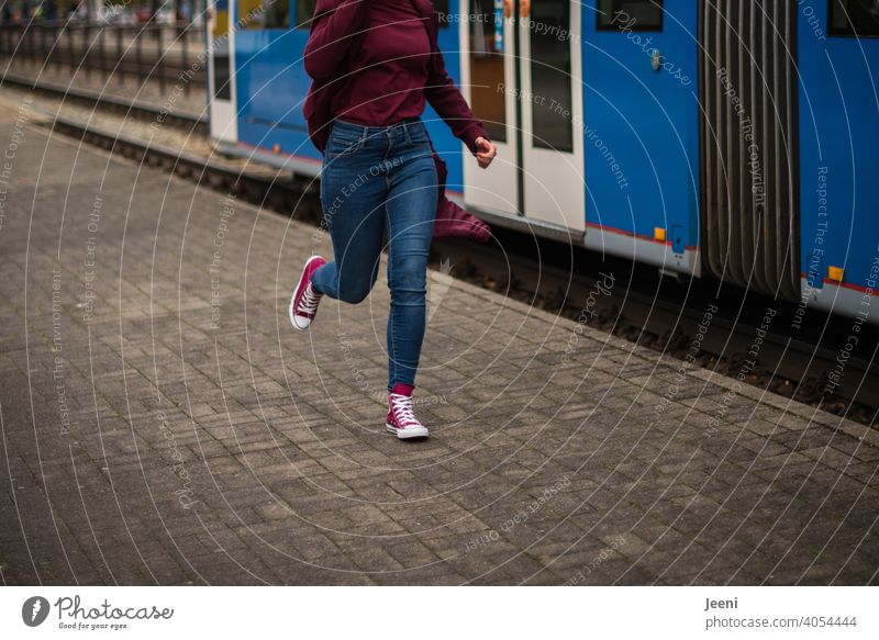 Der Zug ist abgefahren | Eine Frau rennt einer abfahrenden Straßenbahn hinterher rennen laufen schnell beeilen verpassen Straßenverkehr Mensch Jeans modern rot