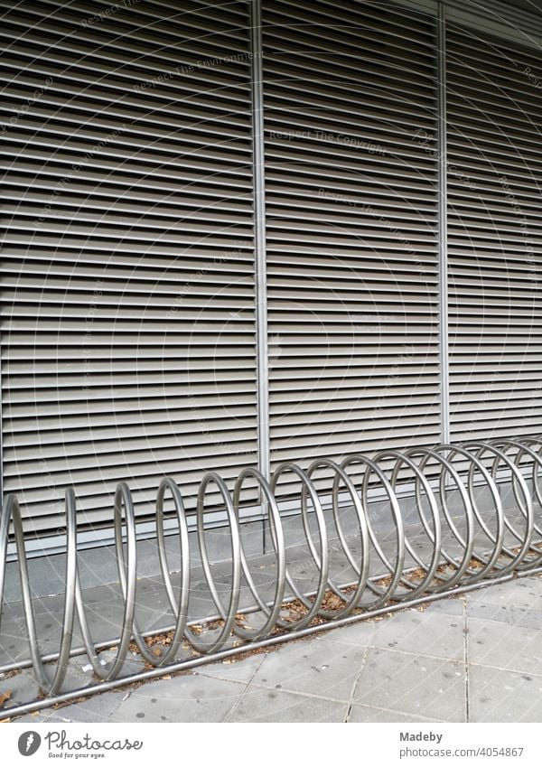 Glänzende Spirale als Fahrradständer und Lamellen als Sonnenschutz vor den Fensterscheiben eines Bürogebäude im Westend von Frankfurt am Main in Hessen Eisen