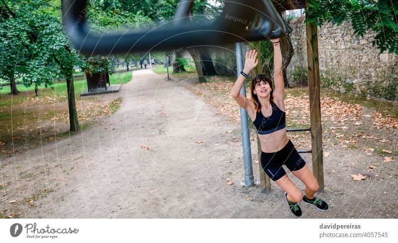 Frau macht Affenübungen auf Ringen Athlet Sportlerin Training Affenstangen Ringübung Park Übung für Affen jung stark erhängen Menschen passen Gesundheit Körper