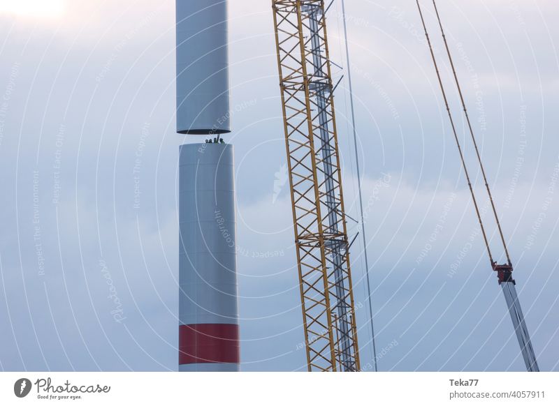 eine moderne Windkraftanlagen-Baustelle Windkraftanlagenbau Baukran Schwerlastkran Windrad Abend Ökostrom Winter Blauer Himmel gelb schwer Farben im Freien