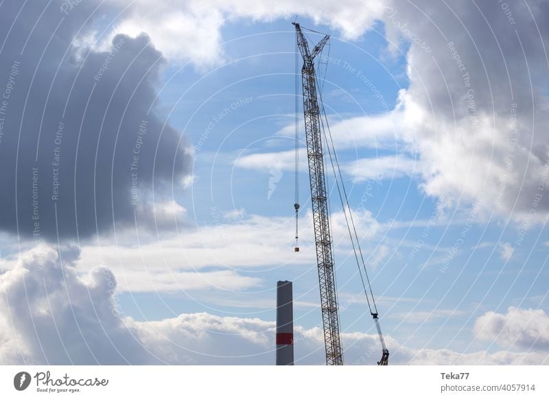 eine moderne Windkraftanlagen-Baustelle Windkraftanlagenbau Baukran Schwerlastkran Windrad Abend Ökostrom Winter Blauer Himmel gelb schwer Farben im Freien