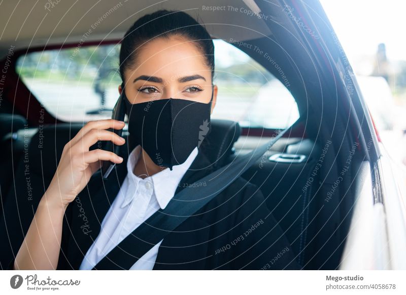 Geschäftsfrau telefoniert im Auto. Frau PKW Mobile Telefon Gesichtsmaske Mundschutz covid-19 reden sprechend Taxi Transport Kabine eine Porträt Erwachsener