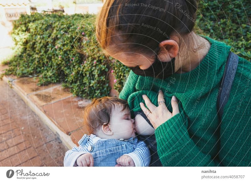 Junge Frau stillt ihr Baby im Freien an einem sonnigen Tag jung Mutter Mama Familie Stillen grün Feiertage Freizeit Gesundheit blond Pflege Kindheit