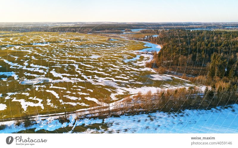 Saisonwechsel. März ländliche Landschaft. Winterkulturen und gepflügtes Feld-Panorama. Schnee Frühling Natur Antenne Hintergrund Baum weiß Wald grün Straße