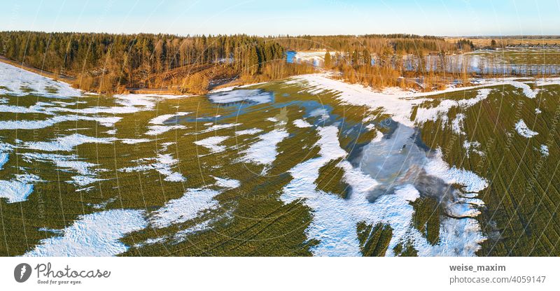 Saisonwechsel. März ländliche Landschaft. Winterkulturen und gepflügtes Feld-Panorama. Schnee Frühling Natur Antenne Hintergrund Baum weiß Wald grün Straße