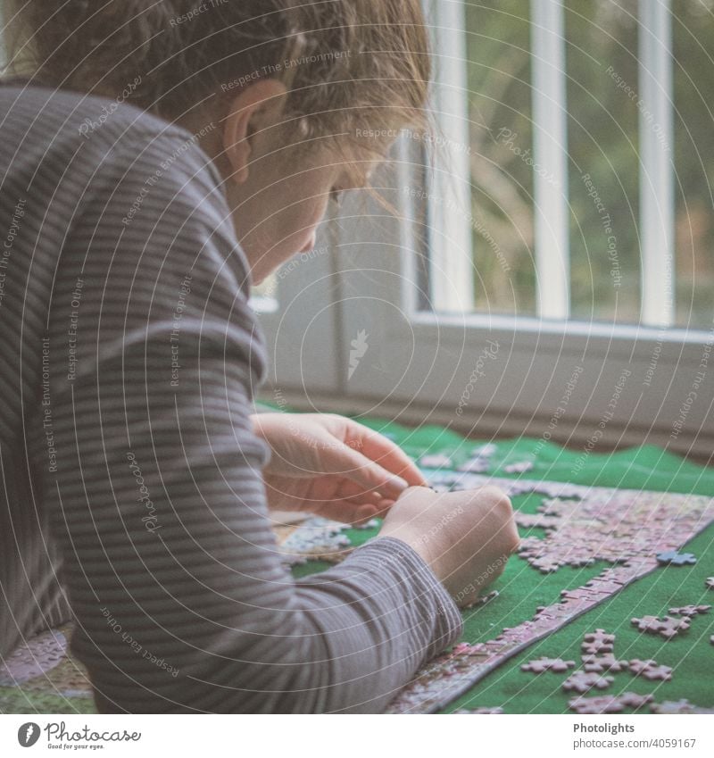 Junge Frau schaut sich ein Puzzleteil an puzzlen Farbfoto Teile u. Stücke Freizeit & Hobby Spielen mehrfarbig Spielzeug Innenaufnahme Suche Problemlösung