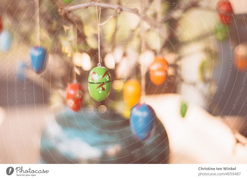 Bunte Ostereier aus Holz hängen an den Zweigen, die als Osterdekoration in einer Vase stehen Ostern osterdekoration Dekoration Osterfest Holzeier bunt