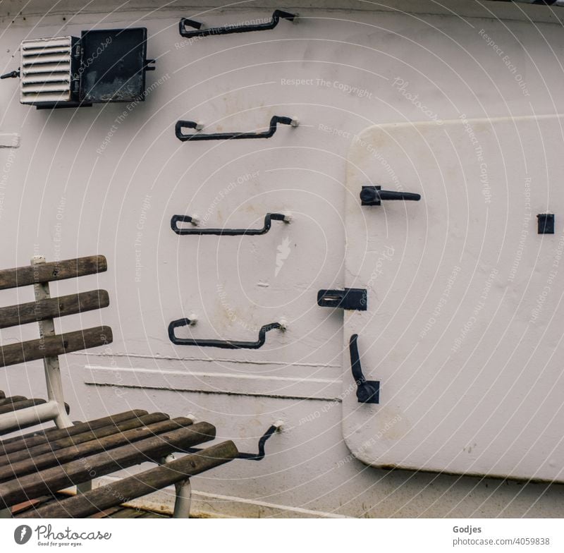 Sitzgelegenheit vor einer metallenen Schiffswand mit Stufen und Luke Schifffahrt Wasserfahrzeug Sitzbank Tür Treppe Leiter Außenaufnahme Tag Farbfoto Hafen alt