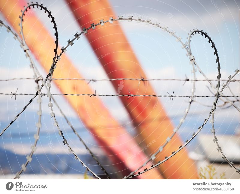 Stacheldraht über den Zaun auf einem unscharfen Hintergrund mit Stacheln versehen blau verschwommen Bokeh Hintergrund Borte Begrenzung Konzept Gefahr Eingang