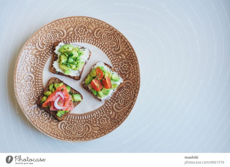 verschiedene Toasts auf Teller, gesundes Frühstück mit Lachs, Avocado, Frischkäse, Gurke und roten Zwiebeln Lebensmittel Belegtes Brot Zuprosten Snack Mahlzeit