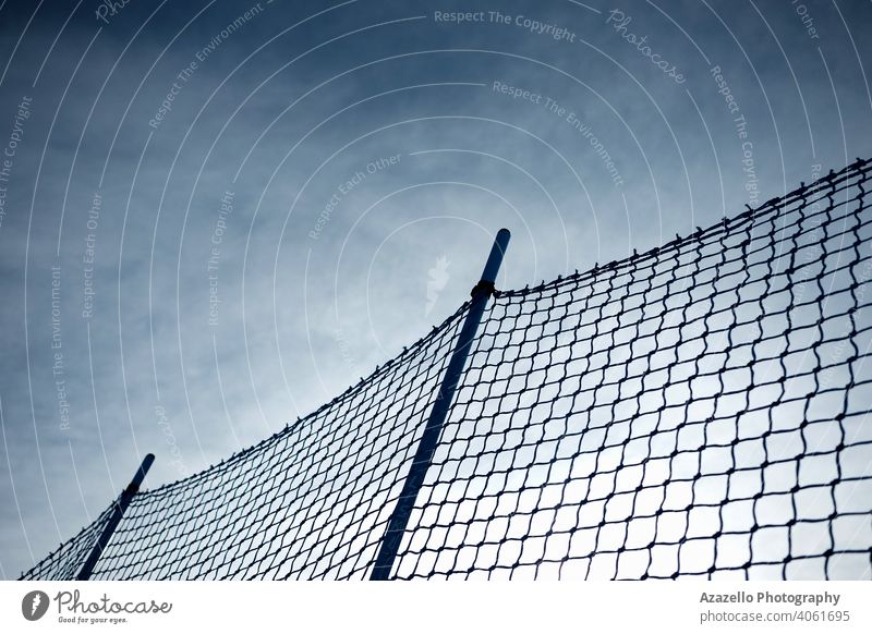 Kunststoff-Netzzaun bei Sonnenuntergang. Netz Hintergrund mit dramatischen Hintergrund. Gegend Atmosphäre Barriere Borte Geflecht Wolken Konstruktion Gefahr