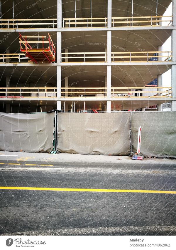 Modernes Bürogebäude im Rohbau mit Bauzaun und gelber Fahrbahnmarkierung auf dem grauen Asphalt im Westend von Frankfurt am Main in Hessen Baustelle Hochhaus