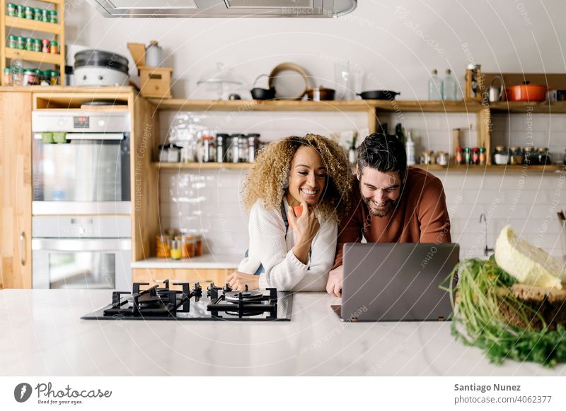 Ehepaar schaut in der Küche auf einen Laptop. Lebensmitte Paar Liebe Essen zubereiten heimwärts gemütlich Kaukasier Partnerschaft vorbereitend Frau Glück Person