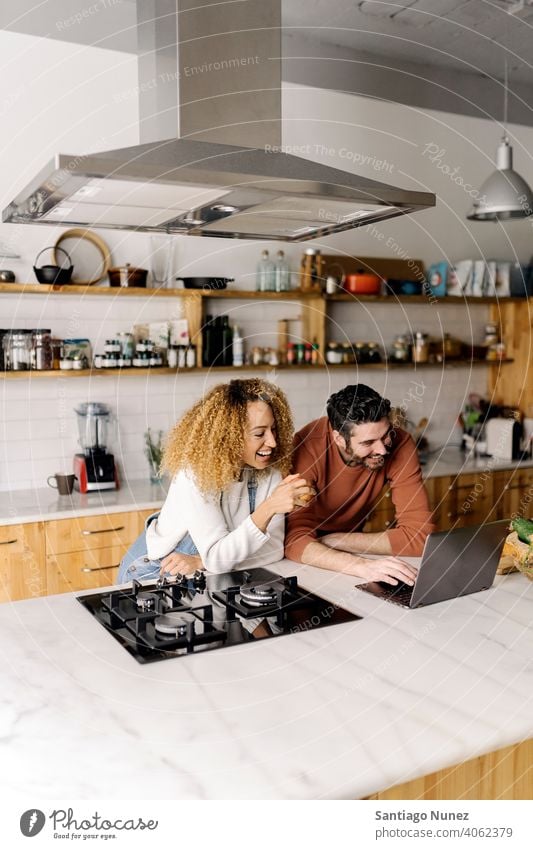 Ehepaar schaut in der Küche auf einen Laptop. Lebensmitte Paar Liebe Essen zubereiten heimwärts gemütlich Kaukasier Partnerschaft vorbereitend Frau Glück Person