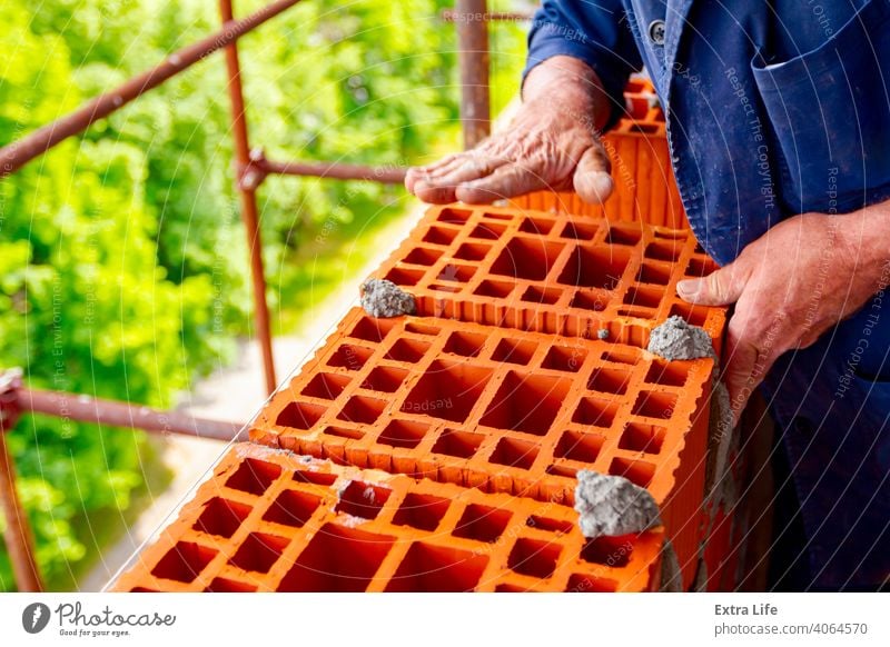 Arbeiter baut Mauer mit roten Blöcken und Mörtel Genauigkeit genau Aktivität Architektur Klotz Baustein Maurer Maurerarbeiten Mauerwerk Bauherr Baustelle